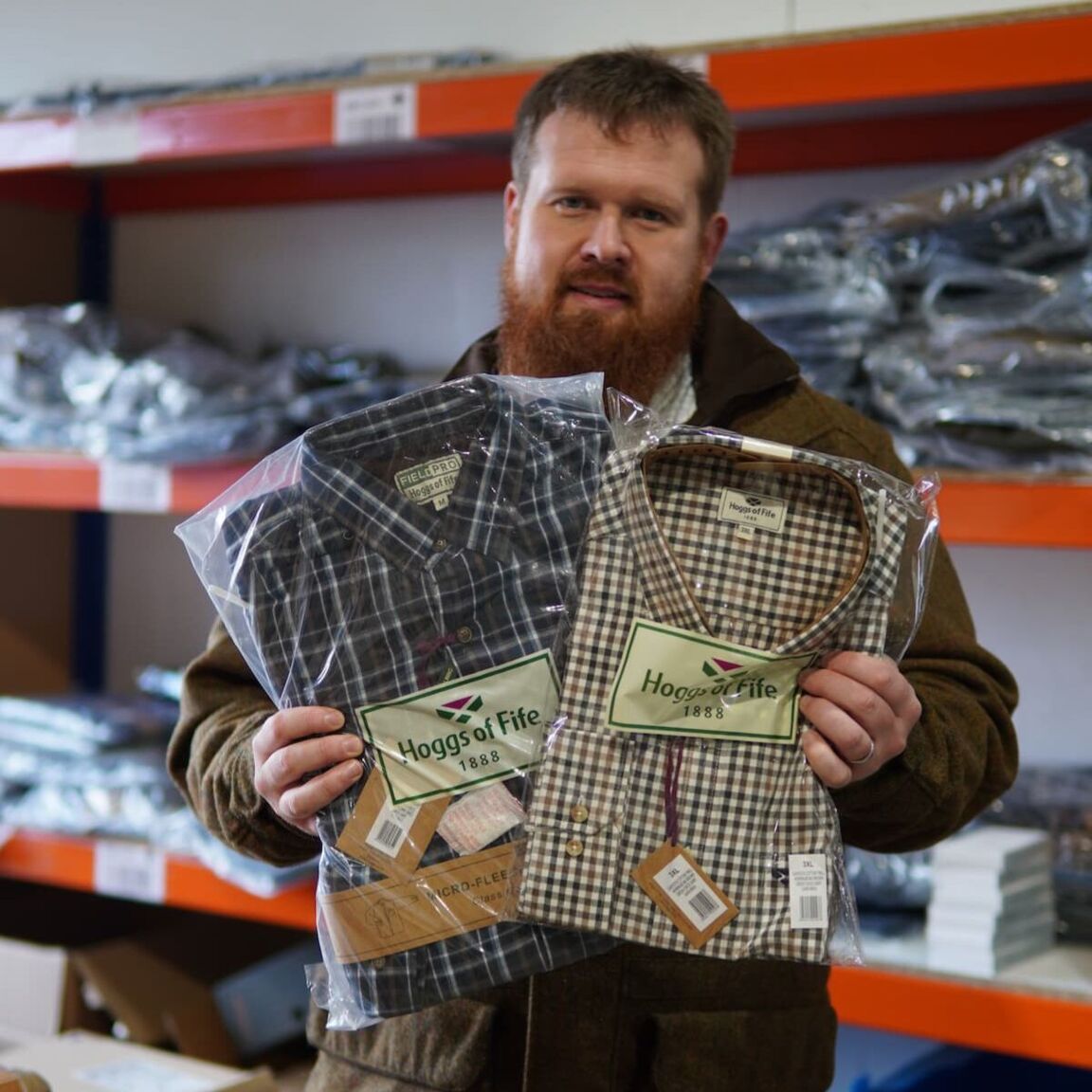 Matt holding two Hoggs of Fife shirts in front of the camera.