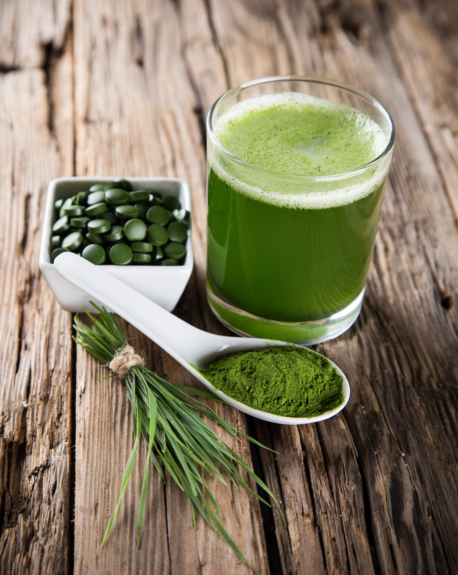 Green juice, bowl of chlorella tablets and spoonful of chlorella powder