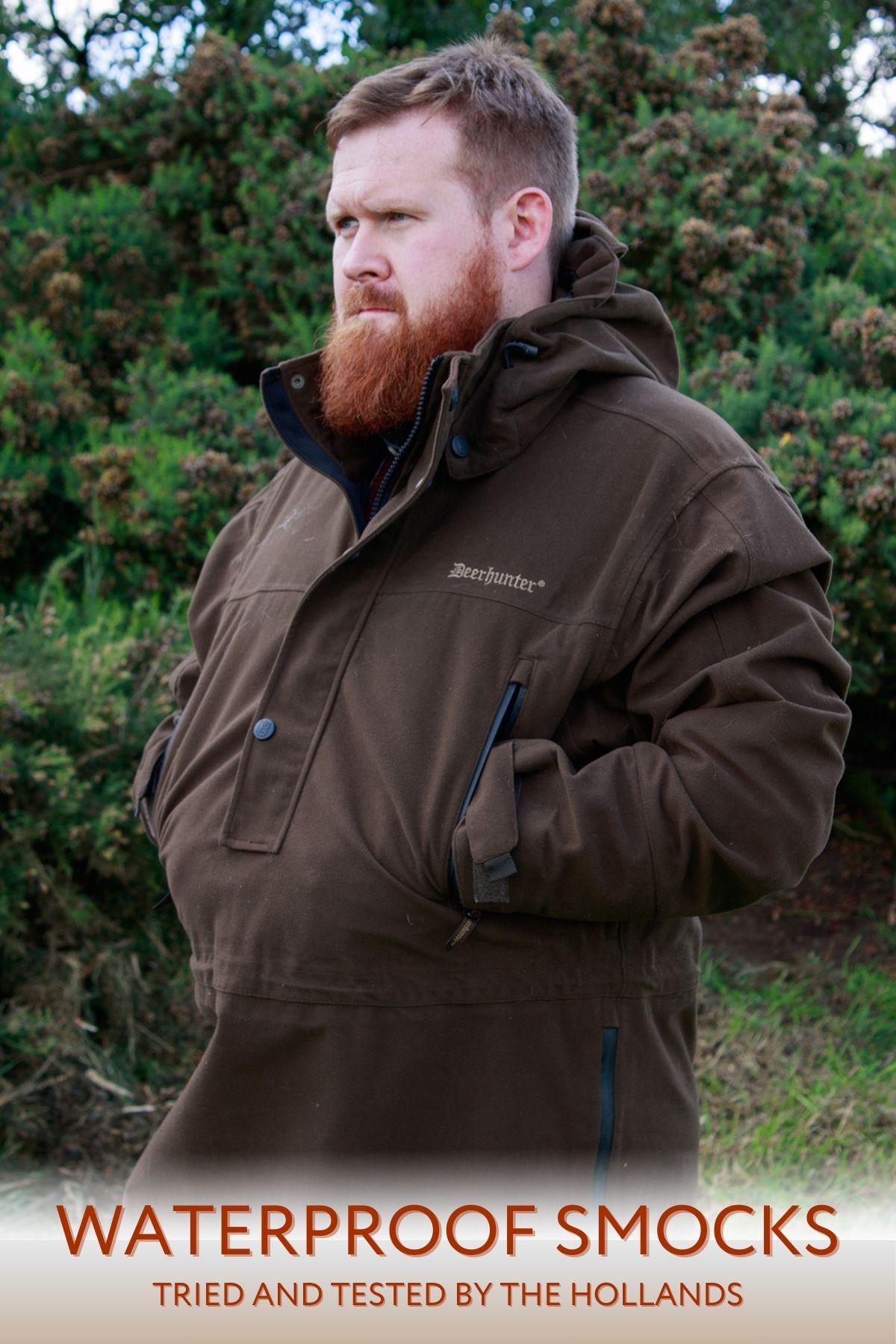 man in a dark brown smock with his hand in pockets, staring sideways