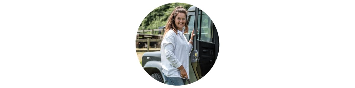 a woman in white shirt standing next to a land rover defender.