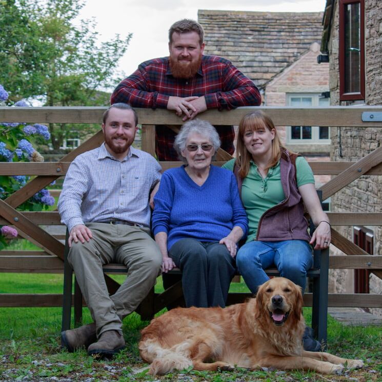 Two men and two women, one with white hair, posing for a family photo on a bench.